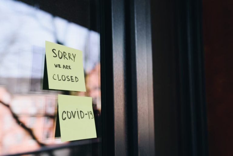 Image of sticky notes on a glass door reading "Sorry we are closed due to COVID 19"